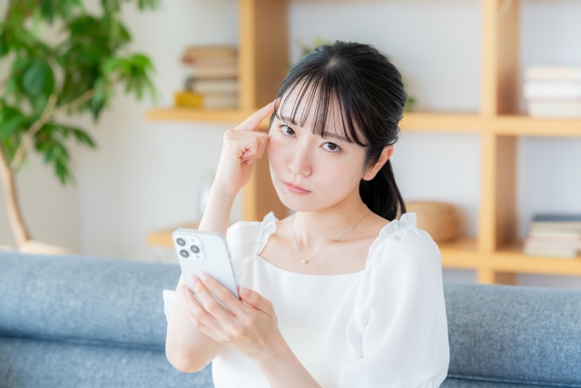スマホを見ながら悩む女性