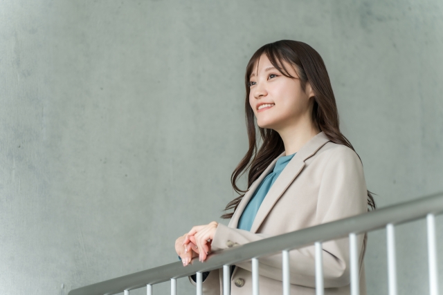 屋内の手すりで外を眺めるビジネスウーマン