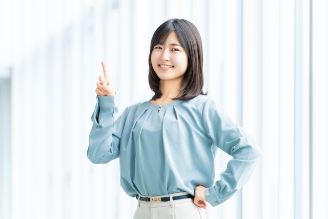 人差し指を立てて案内する笑顔の女性