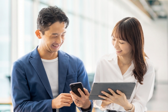 タブレットとスマホを見ながら話す男女