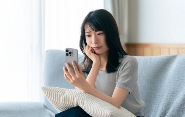 スマホを見て悩む女性