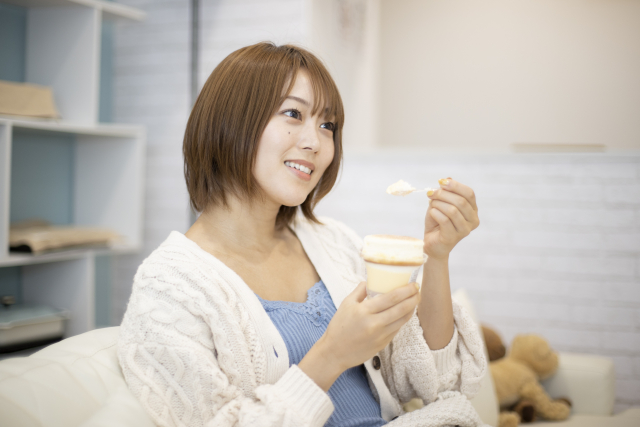 コンビニスイーツを食べる女性