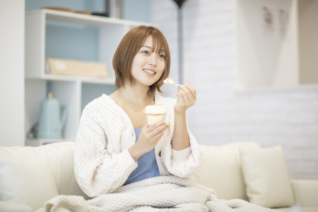 コンビニスイーツを食べる女性
